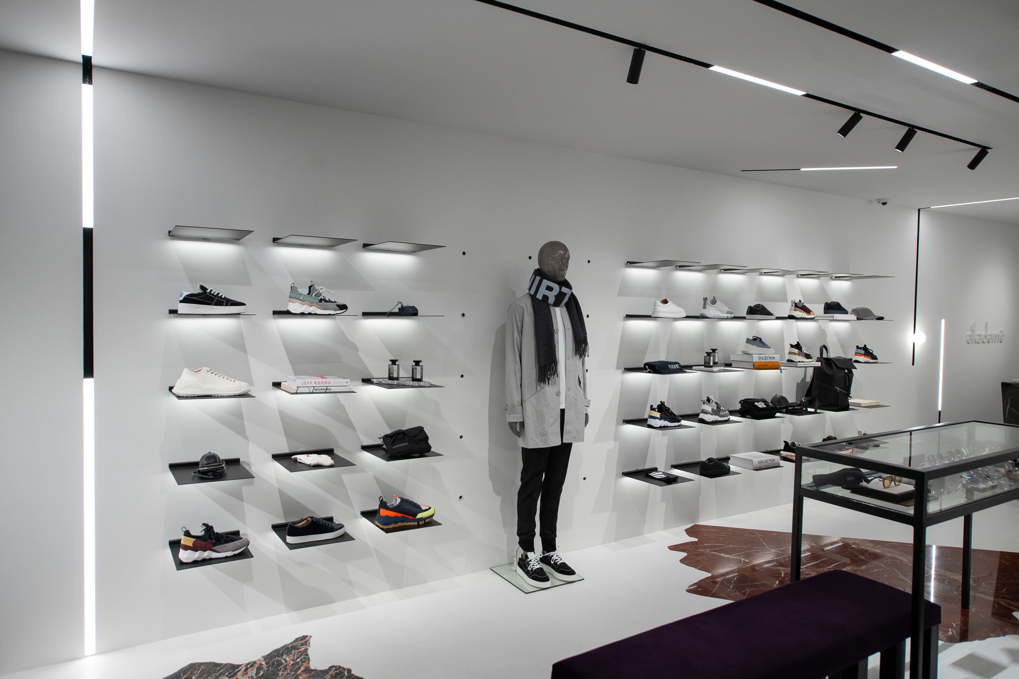 Vista detallada del espacio comercial de la tienda Ekademe de Utrecht, con elegantes prendas en estanter&iacute;as met&aacute;licas minimalistas y electrificadas de Visplay.