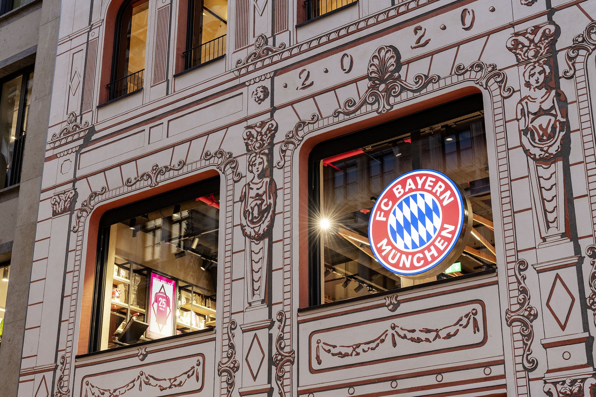 Fassade eines Geb&auml;udes mit FC Bayern M&uuml;nchen Logo im Fenster.