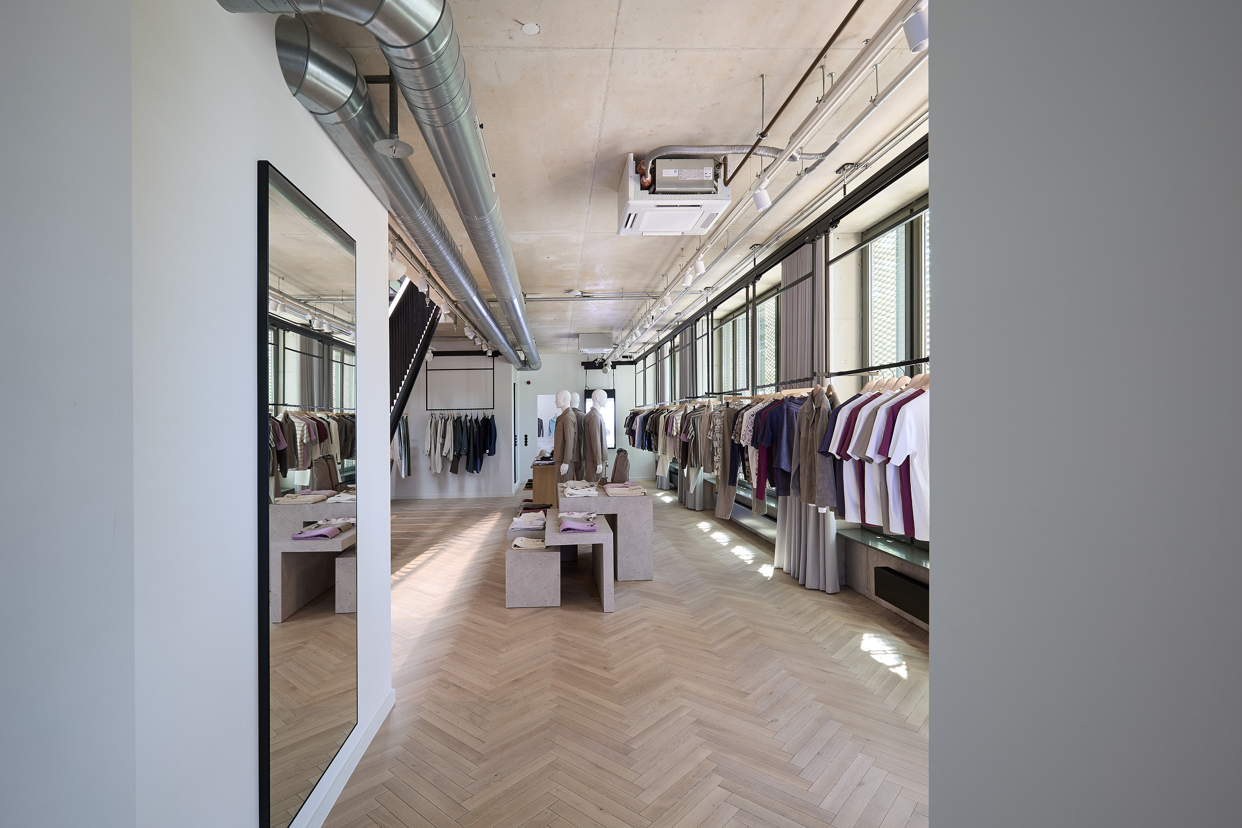 Un showroom avec des syst&egrave;mes muraux modulaires o&ugrave; v&ecirc;tements et accessoires sont pr&eacute;sent&eacute;s sur des &eacute;tag&egrave;res et des supports m&eacute;talliques bien structur&eacute;s.