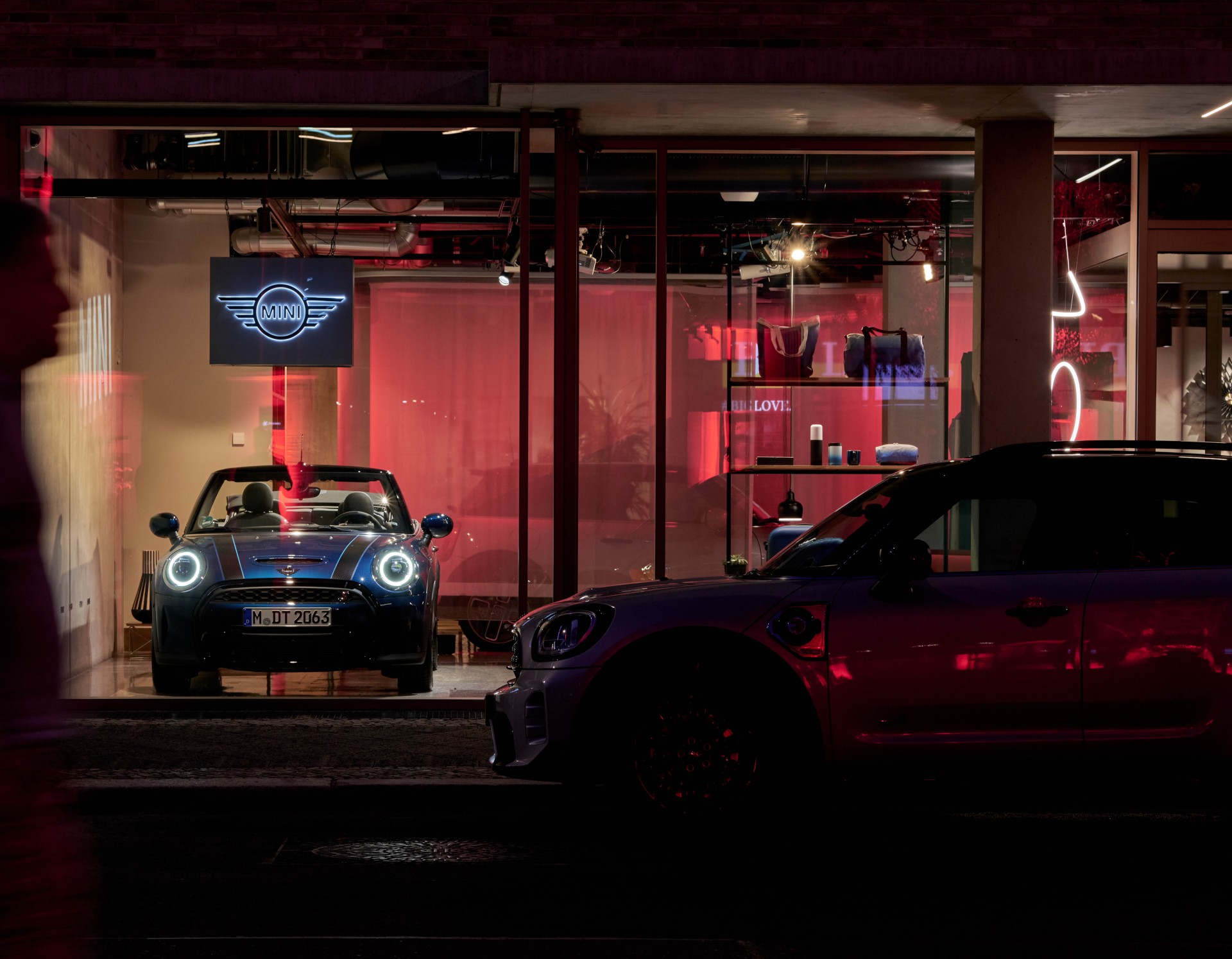 Rot beleuchtetes Schaufenster eines Geb&auml;udes mit darin ausgestellten Autos des Fahrzeugherstellers MINI.