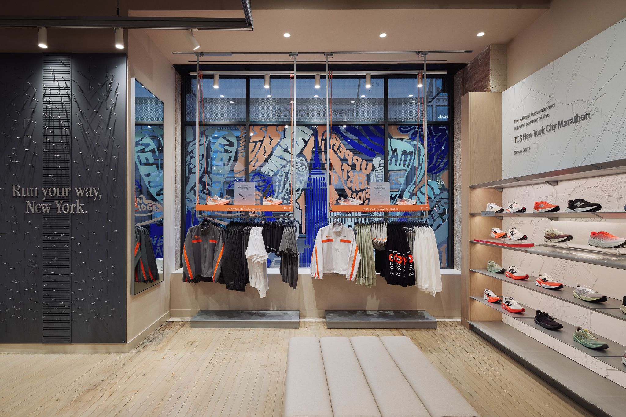 Innenansicht eines Sportgesch&auml;fts mit Laufbekleidung, Schuhregal und Wandtext 'Run your way, New York.'