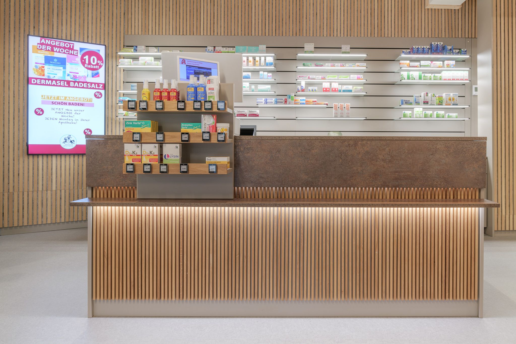 Kassenbereich der Rasso Apotheke mit eingesetzten Invisible 6 Tablaren von Visplay.