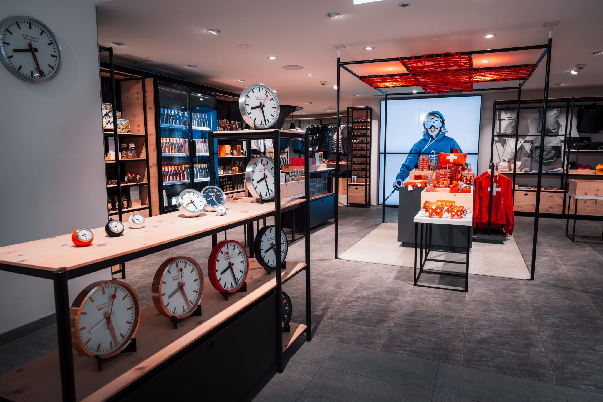 Verkaufsraum mit Regalen voller Uhren und einem Schaufenster mit Schweizer Souvenirs und einer Schaufensterpuppe