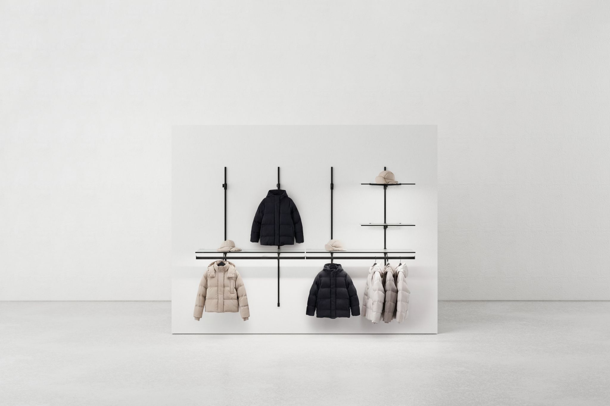 Minimalist coat rack system with black rods on a white wall holding several jackets and hats