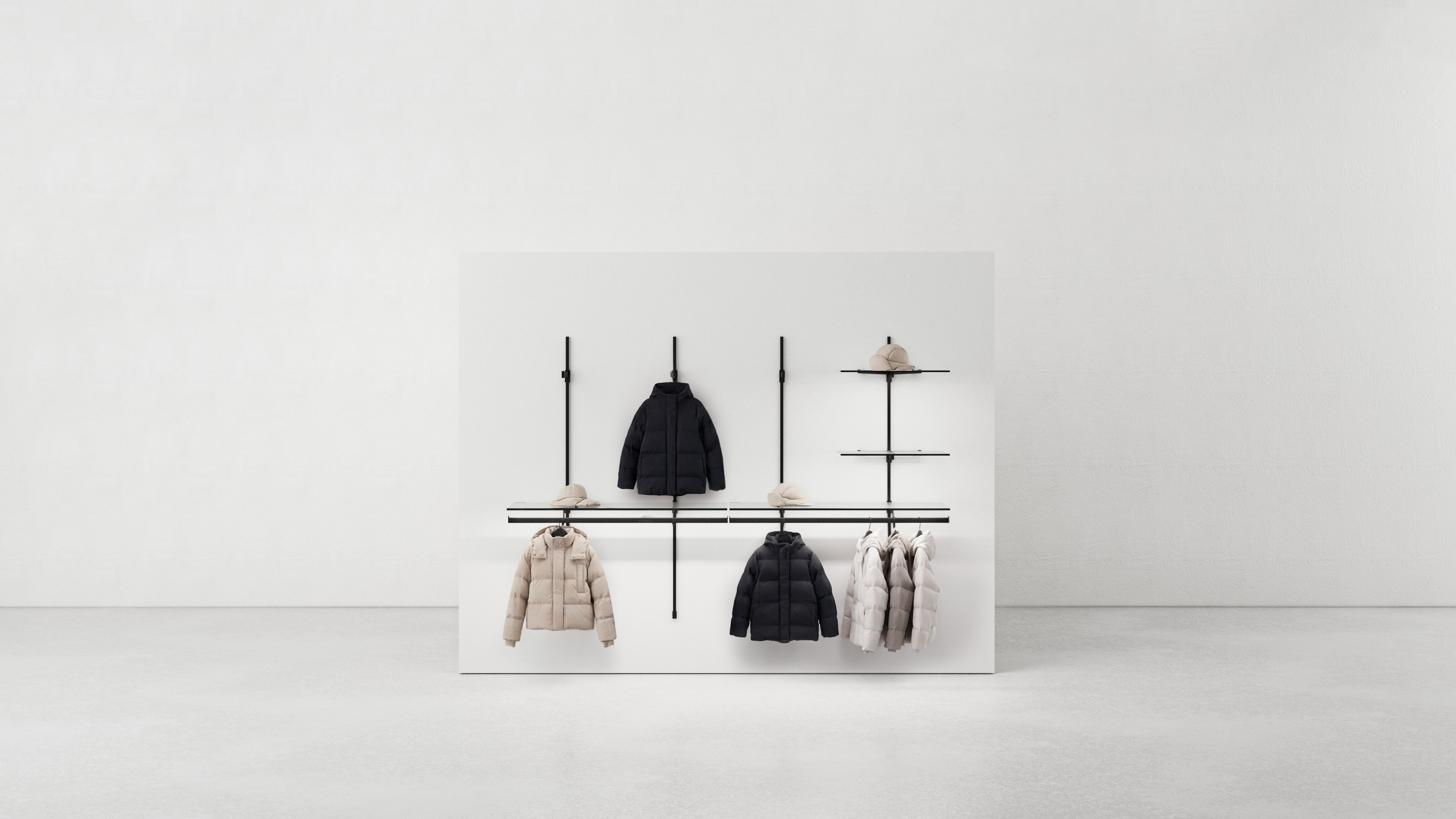 Syst&egrave;me de porte-manteaux minimaliste avec des tiges noires sur un mur blanc portant plusieurs vestes et bonnets