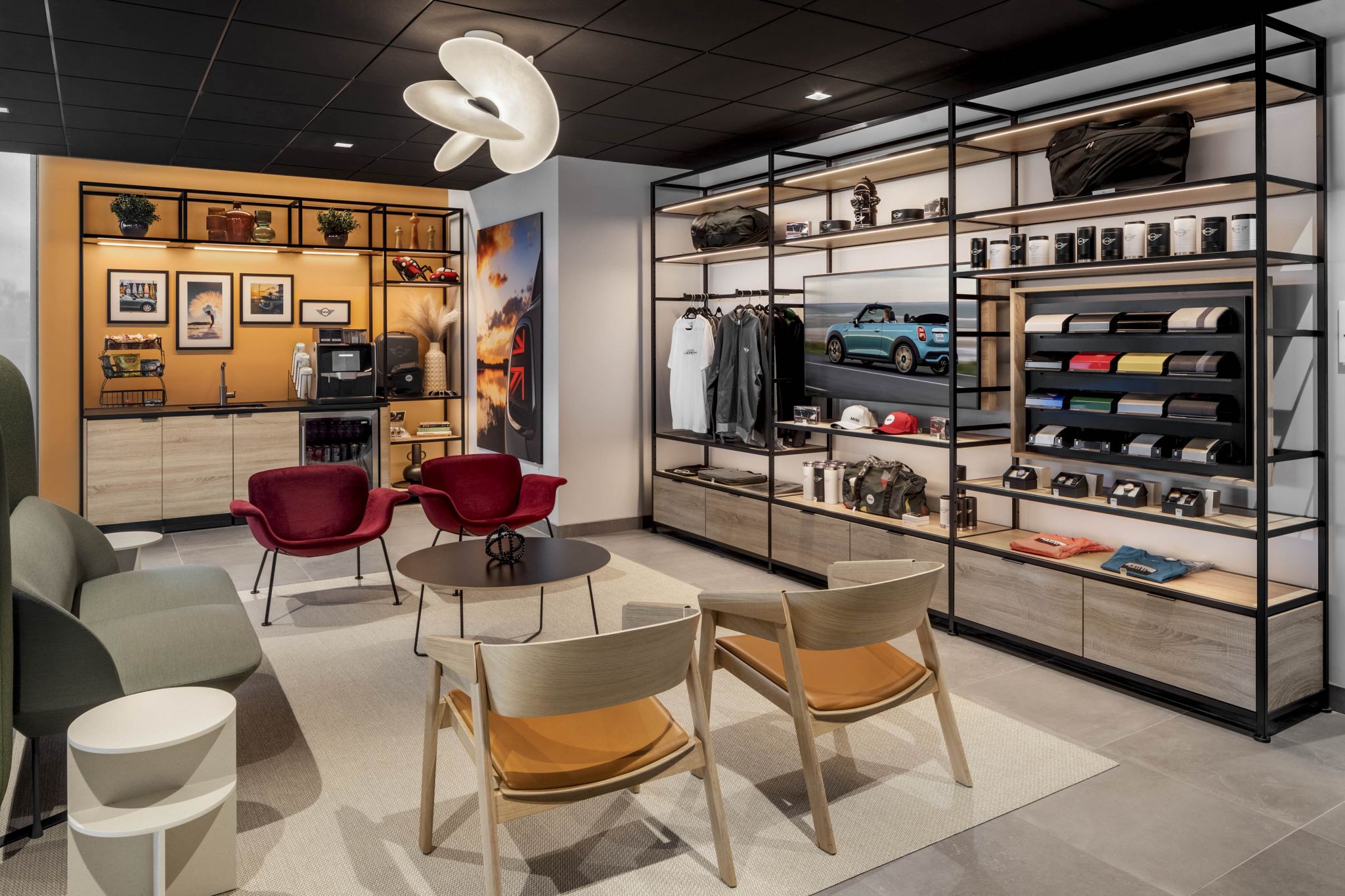 Modern retail space with shelves displaying clothing, bags, Mini models, and a seating area with chairs and tables.