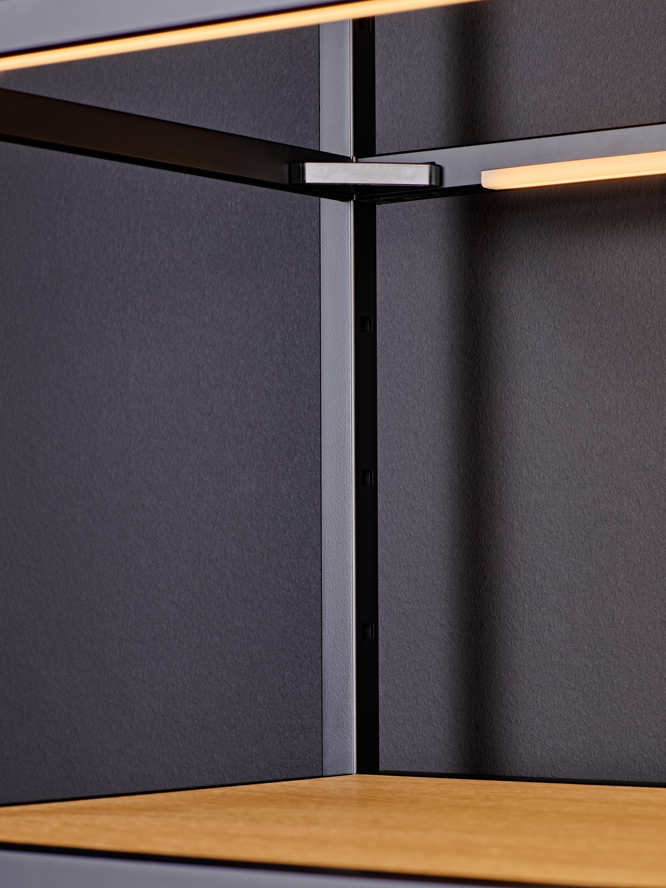 Close-up of a black metal frame with a wooden panel and integrated LED lighting.