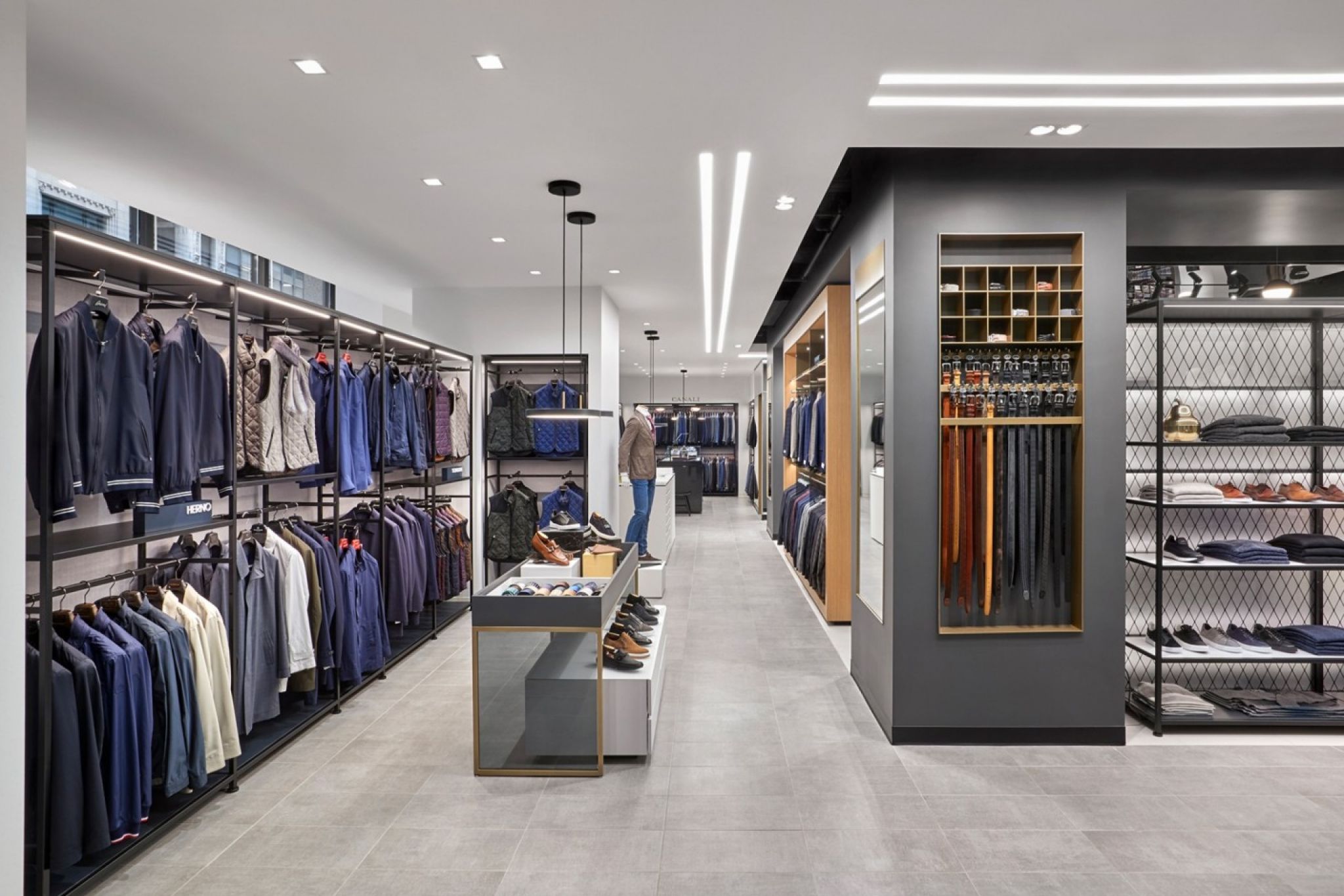 Modern retail space displaying men's clothing, shoes, and accessories in a well-lit, organized layout.