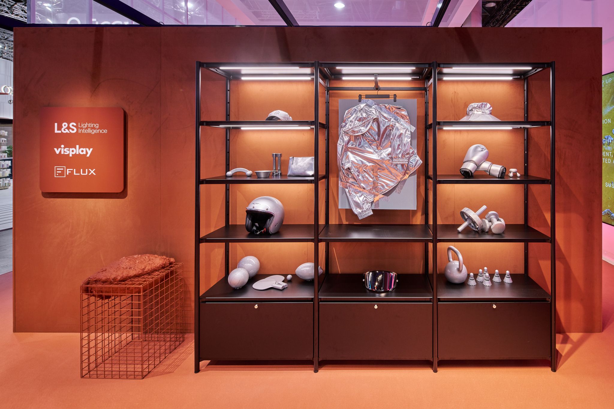 &Eacute;tag&egrave;re m&eacute;tallique noire en trois parties avec objets d&eacute;coratifs argent&eacute;s et fond orange portant les logos L&amp;S Lighting Intelligence, visplay et FLUX