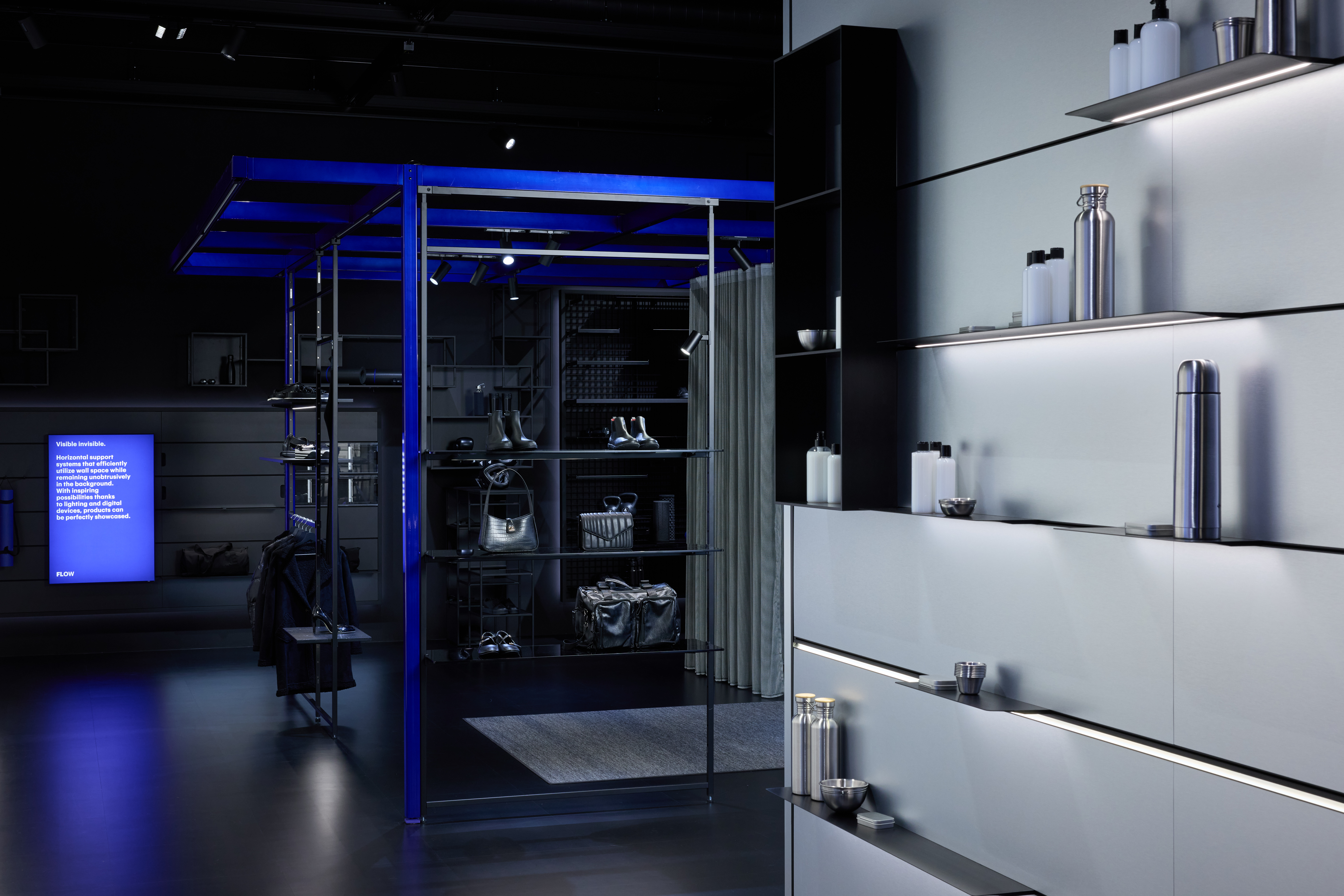 Freestanding blue structural system with shelves and clothing in a bright showroom.