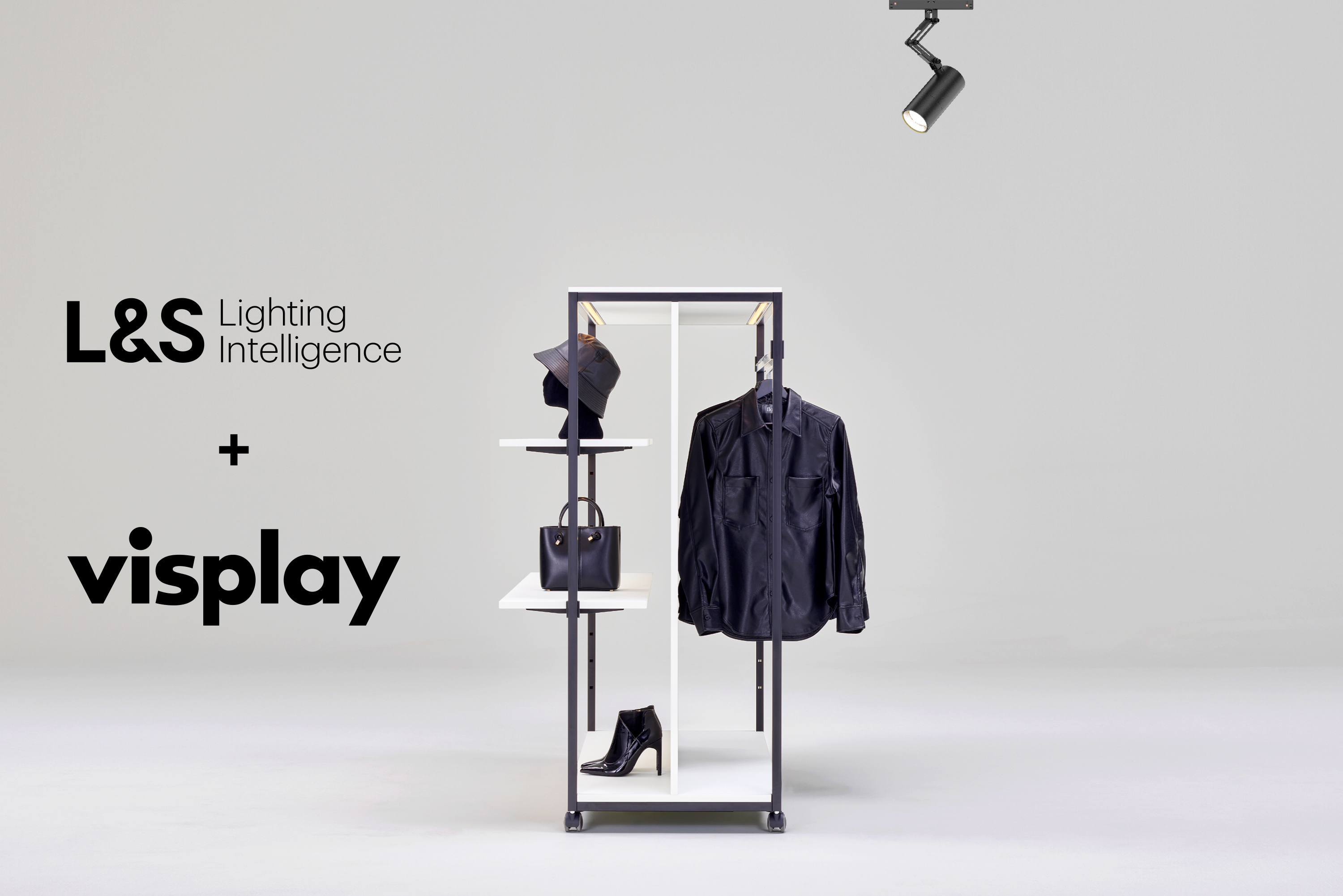 Clothing and accessories displayed on a minimalist black metal frame with white shelves, a single black ceiling spotlight above, and the logos 'L&amp;S Lighting Intelligence' and 'visplay' on the left.